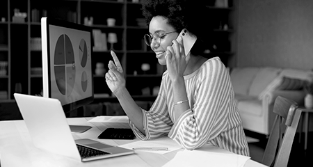 Woman on her phone looking at her monitor and laptop