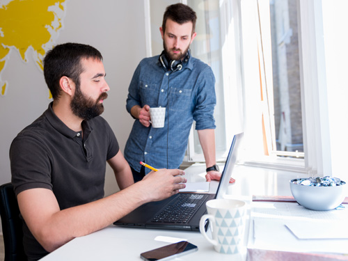 Two programmers reviewing work on a laptop